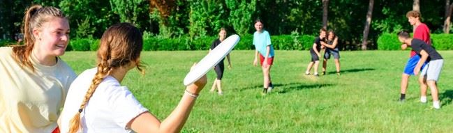 Kids playing frisbee in the park during summer camp