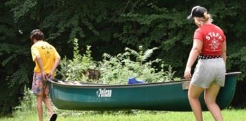 Kids and a camp councilor carrying a canoe.  